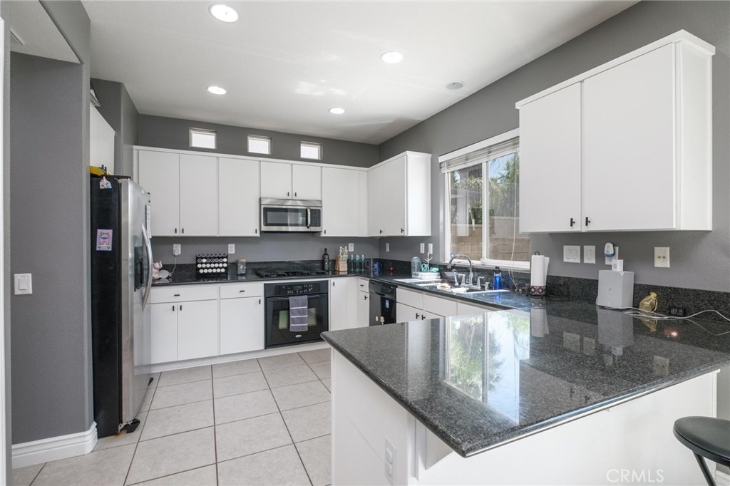 7940 Shadow Trails Lane Jurupa Valley, CA 92509 - Photo 9 of 34 a kitchen with a refrigerator a sink a stove a microwave and cabinets