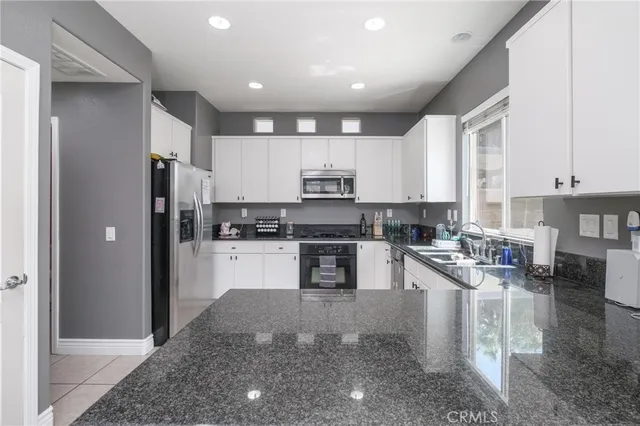 a kitchen with stainless steel appliances granite countertop a refrigerator stove top oven and sink