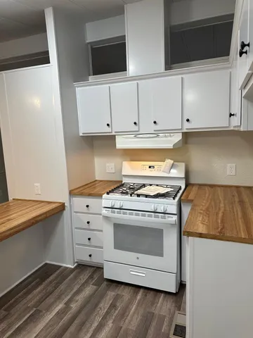 a kitchen with granite countertop white cabinets and white appliances
