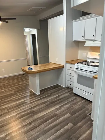 a view of kitchen with granite countertop white cabinets and white appliances