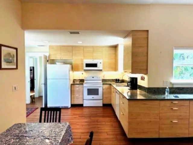 a kitchen with stainless steel appliances granite countertop a sink a stove a refrigerator a washer dryer and white cabinets