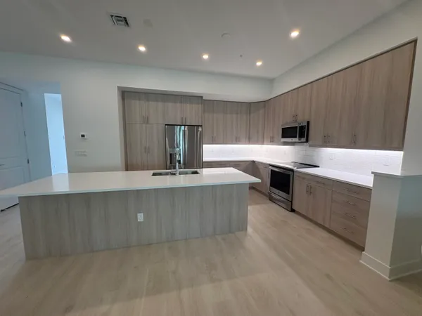 a large kitchen with kitchen island a sink a stove a center island a stove and cabinets