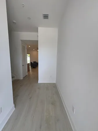 a view of a hallway with wooden floor and a bathroom