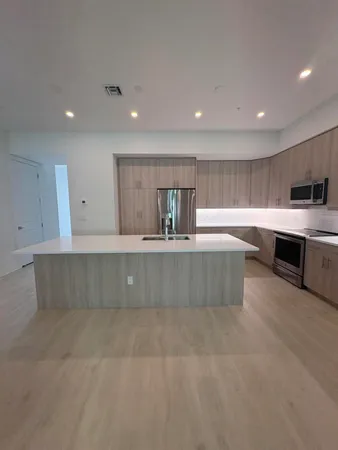 a large kitchen with stainless steel appliances a large counter top a stove and a sink