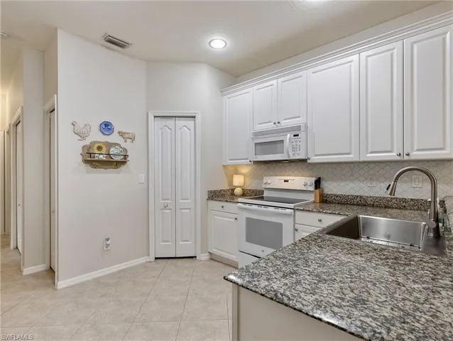 a kitchen with granite countertop white cabinets and stainless steel appliances