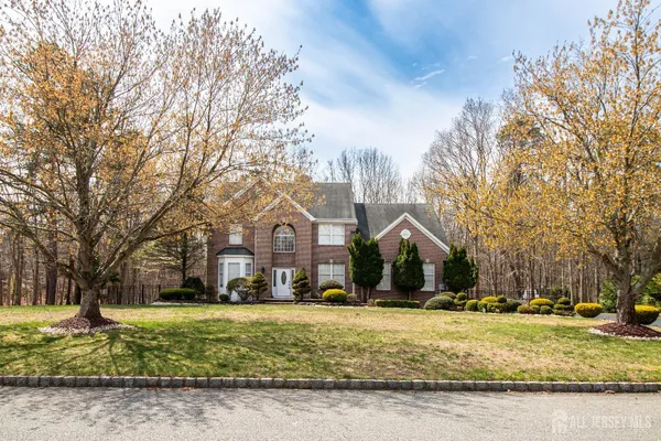 a front view of a house with a yard covered with trees