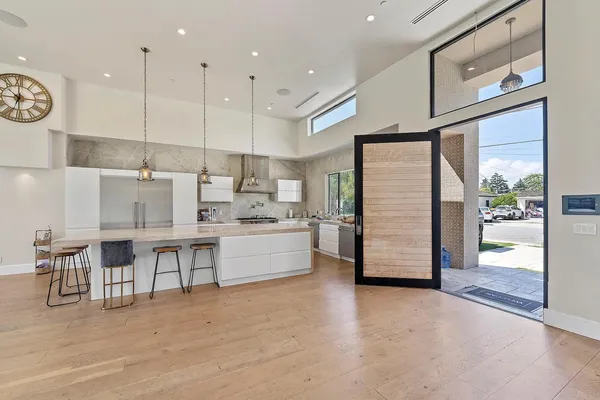a kitchen with stainless steel appliances kitchen island granite countertop a refrigerator a stove and white cabinets with wooden floors