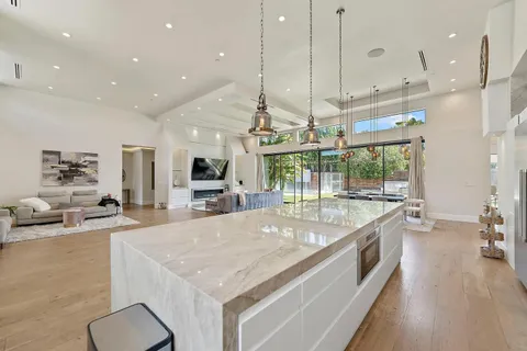 a large kitchen with kitchen island a large counter top a stove a sink and a chandelier