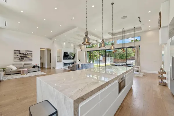 a large kitchen with kitchen island a large counter top a stove a sink and a chandelier