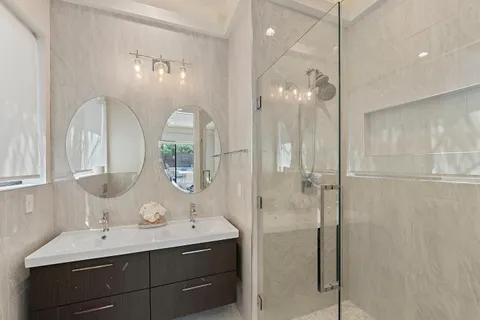 a bathroom with a double vanity sink mirror and shower