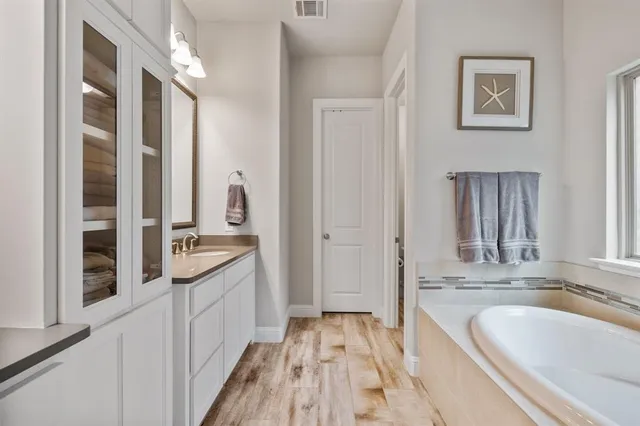 a bathroom with a granite countertop tub sink and mirror