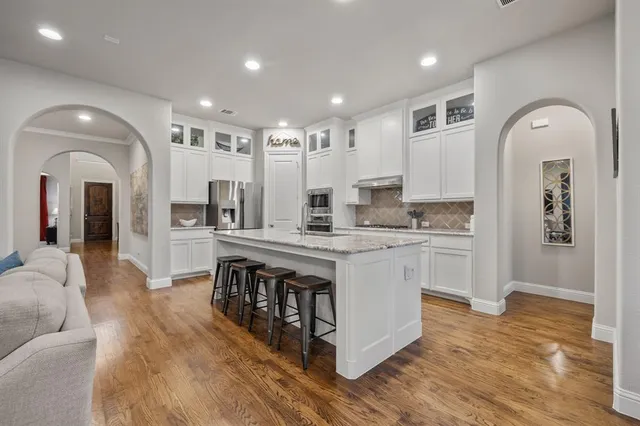 a kitchen with stainless steel appliances granite countertop a stove a sink dishwasher and a refrigerator with wooden floor