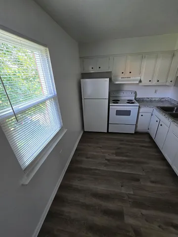 a kitchen with white cabinets and window