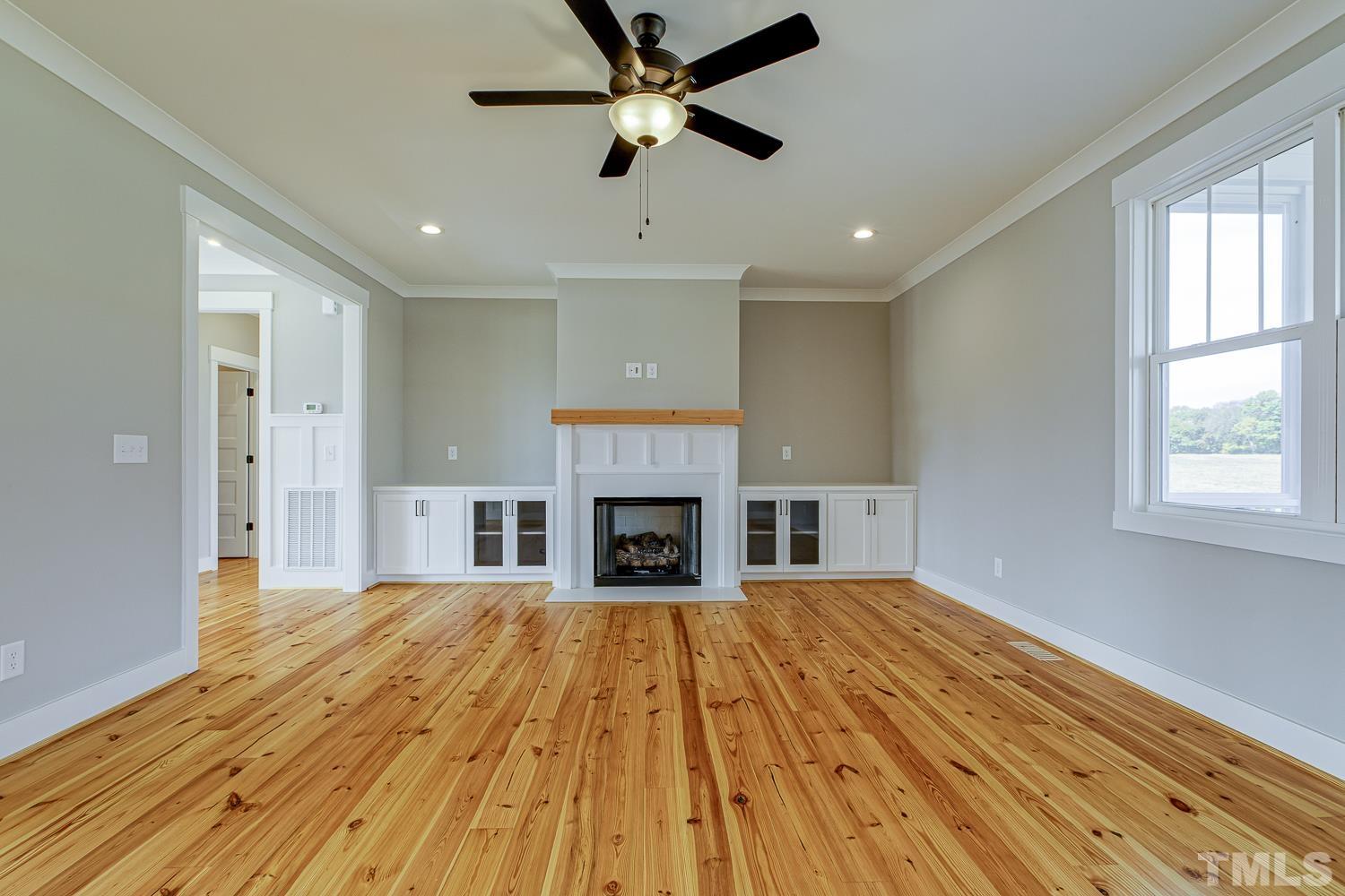 742 River Road Fuquay-Varina, NC 27526 - Photo 12 of 68 a view of a livingroom with a fireplace a ceiling fan and wooden floor