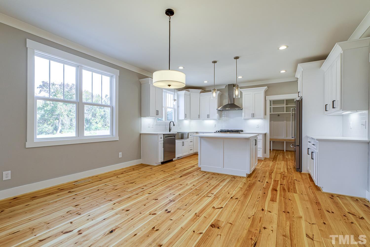 742 River Road Fuquay-Varina, NC 27526 - Photo 16 of 68 a large kitchen with stainless steel appliances kitchen island granite countertop a sink window and wooden floor