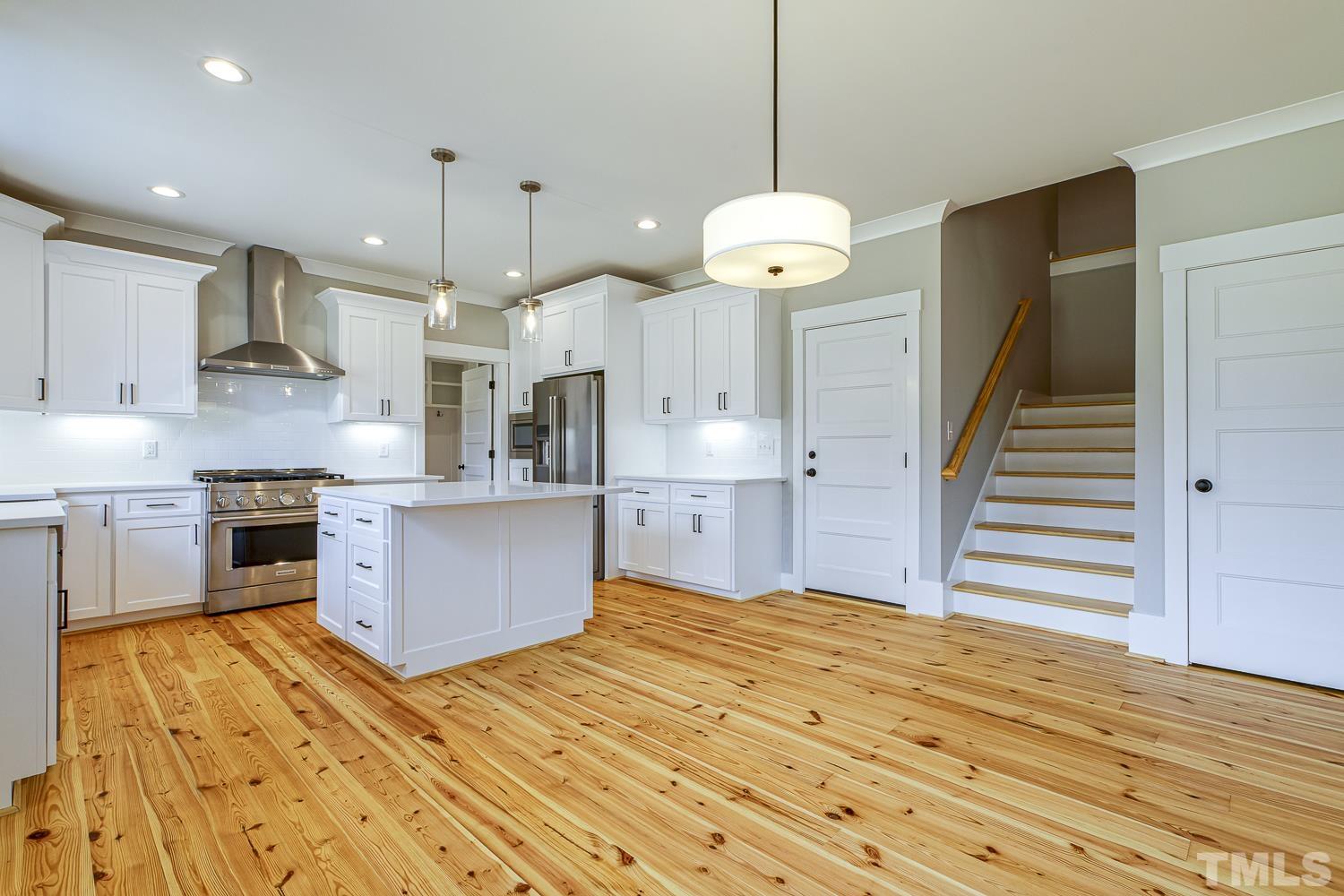 742 River Road Fuquay-Varina, NC 27526 - Photo 17 of 68 a large kitchen with stainless steel appliances kitchen island granite countertop a stove a refrigerator and a view of living room