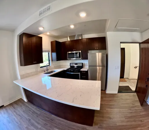 a large kitchen with stainless steel appliances a large counter top a refrigerator and a stove