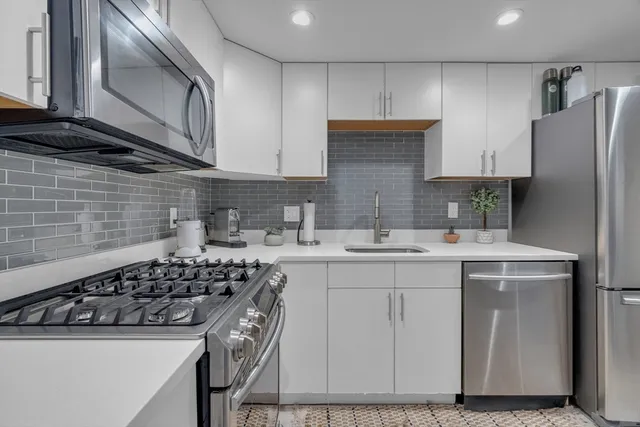 a kitchen with stainless steel appliances a sink stove and cabinets