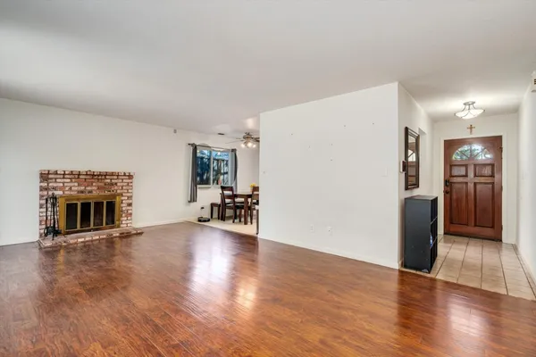 a view of a livingroom with a fireplace a ceiling fan and windows