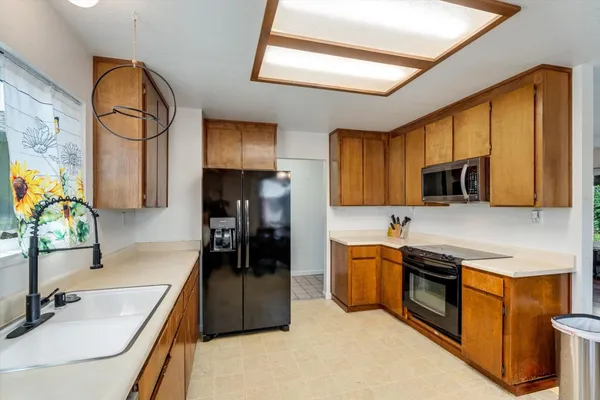 a kitchen with stainless steel appliances granite countertop a sink a stove top oven a counter space and cabinets