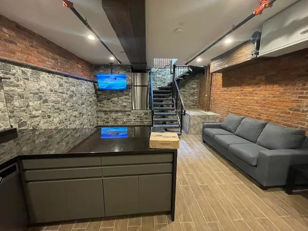 a living room with stainless steel appliances kitchen island granite countertop furniture and a flat screen tv