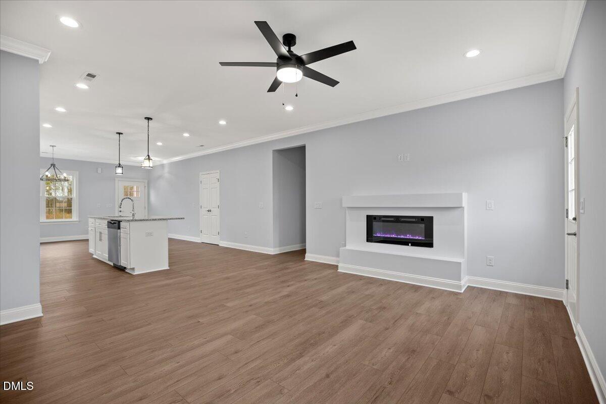 1300 Nick Coley Road Whitakers, NC 27891 - Photo 21 of 47 an empty room with wooden floor a kitchen view and a ceiling fan