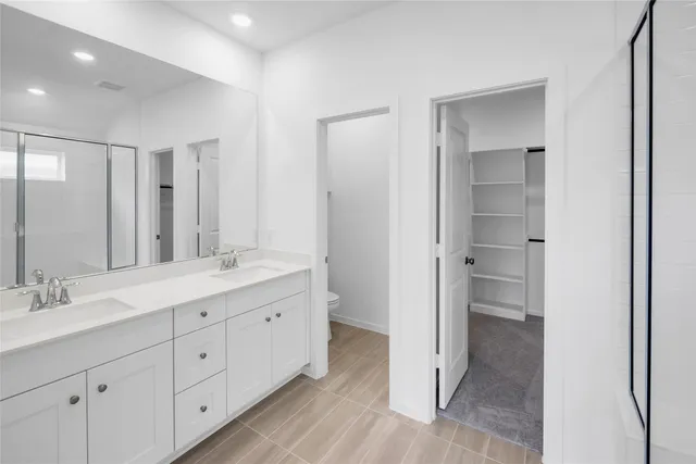 a spacious bathroom with a double vanity sink a mirror and a shower