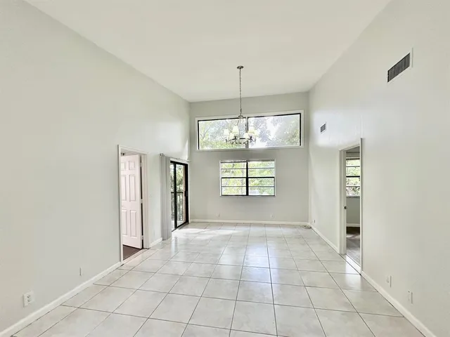 a view of an empty room with window and chandelier