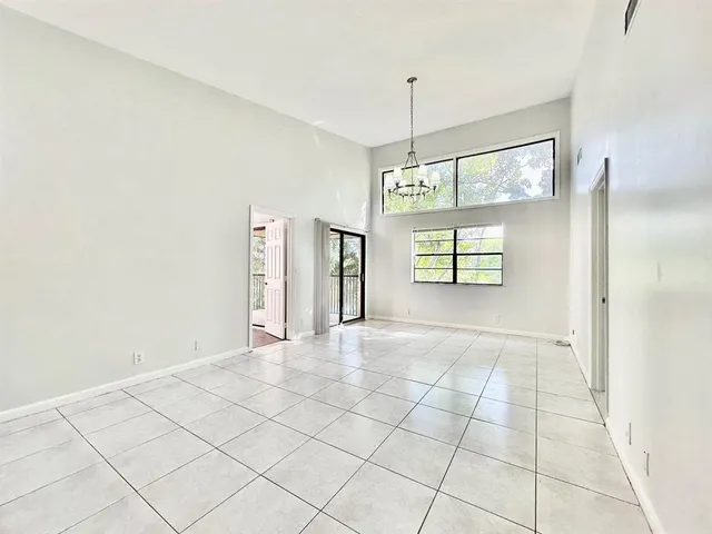 a view of an empty room with window and chandelier fan