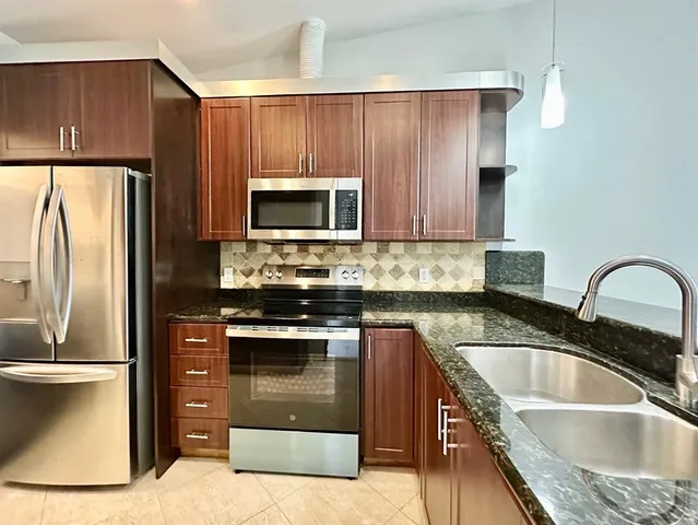 a kitchen with granite countertop a refrigerator stove and microwave