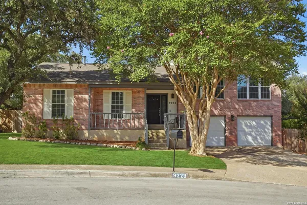 a front view of a house with a garden and tree