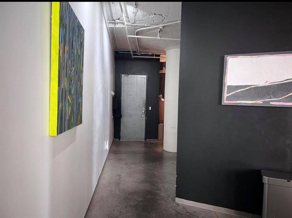 1122 Jackson Street, Unit 514 Dallas, TX 75202 - Photo 22 of 40 Hallway featuring a concrete floor, exposed ceiling conduits, a white painted wall, and a dark accent wall