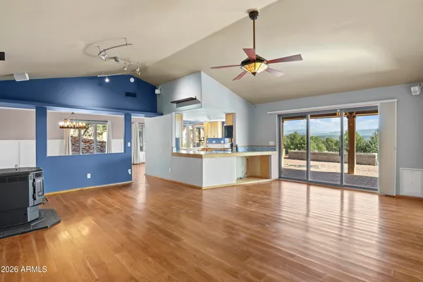 a view of a big room with wooden floor a ceiling fan and windows