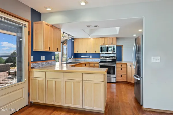 a kitchen with stainless steel appliances granite countertop a refrigerator oven stove a sink and dishwasher with wooden floor