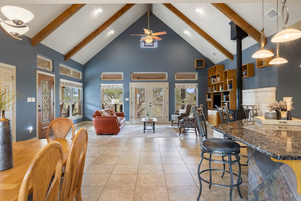232 Crooked Oak Round Mountain, TX 78663 - Photo 13 of 40 Dining room featuring high vaulted ceiling, a wood stove, beamed ceiling, a ceiling fan, and recessed lighting