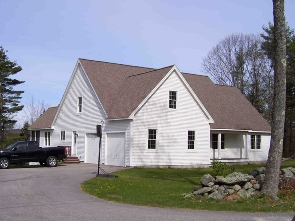 a view of a white house next to a yard and road