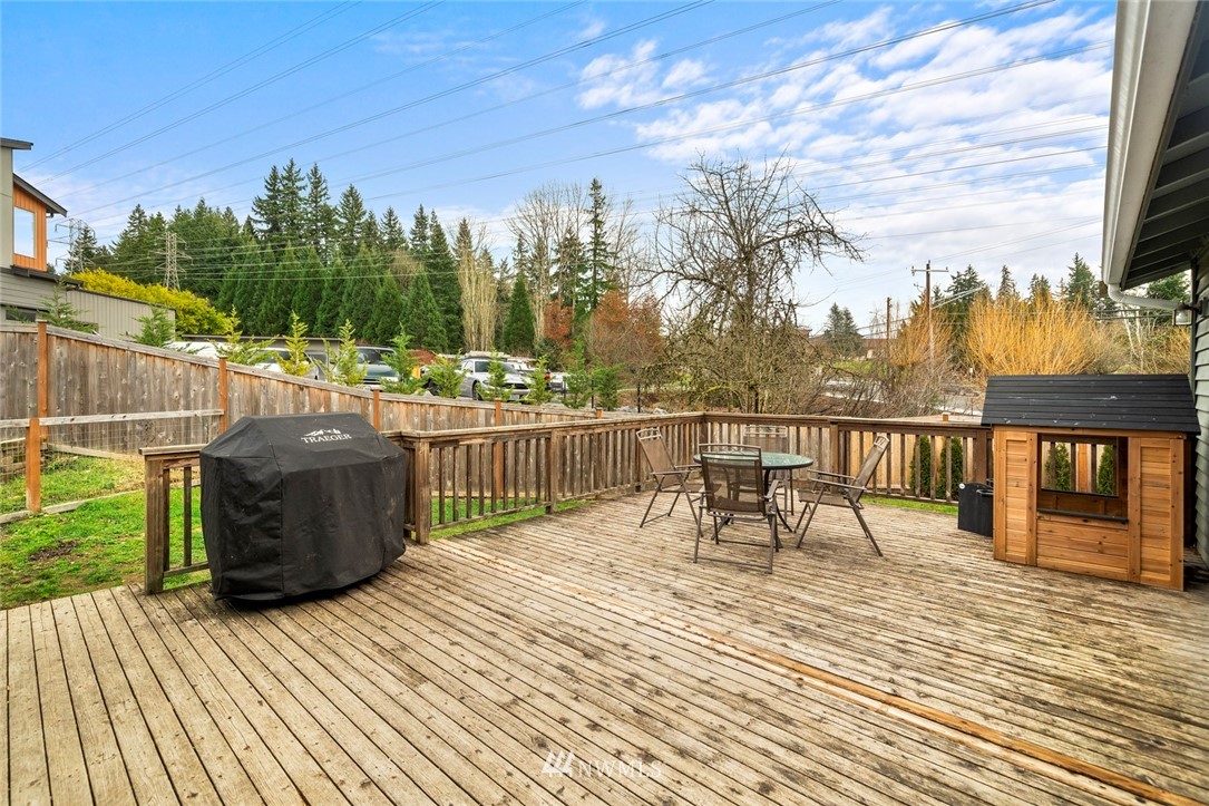 2202 179th Street Southeast Bothell, WA 98012 - Photo 23 of 31 a view of a roof deck with table and chairs a barbeque with wooden floor and fence