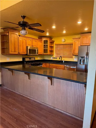 a kitchen with stainless steel appliances granite countertop a sink a stove and a wooden floors