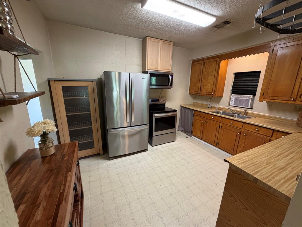 8041 Highway 11 Whitewright, TX 75491 - Photo 12 of 14 a kitchen with stainless steel appliances a stove refrigerator sink and microwave