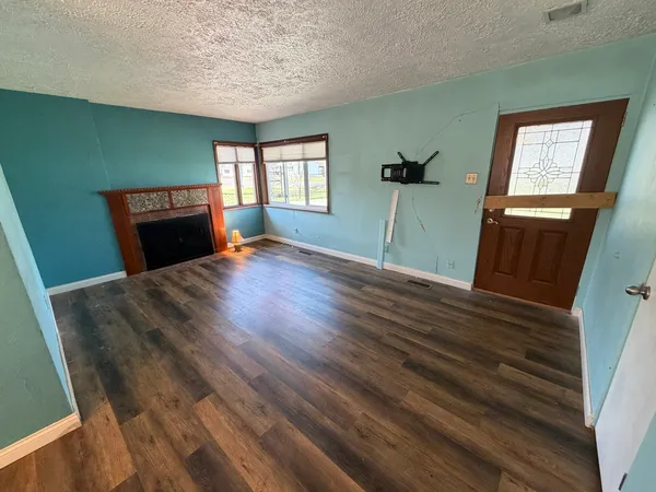 a view of a livingroom with wooden floor and a fireplace
