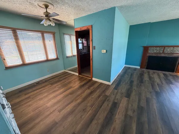a view of a room with wooden floor ceiling fan and a kitchen