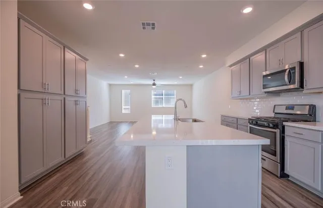 a kitchen with a refrigerator a stove top oven and white cabinets