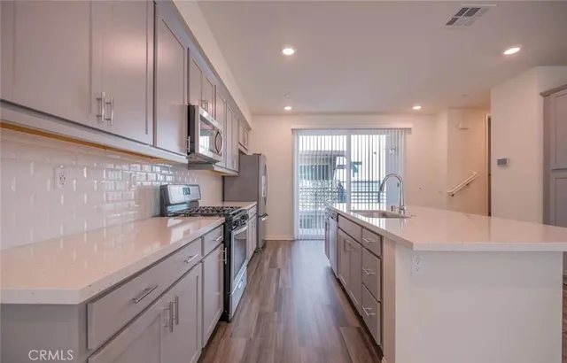 a kitchen with stainless steel appliances a refrigerator a sink a stove a microwave and island