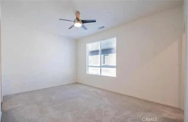 an empty room with windows and fan