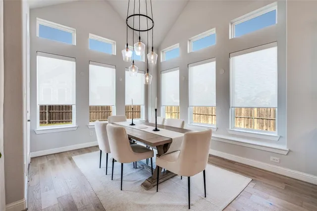 a dining room with wooden floor a chandelier a glass table and chairs