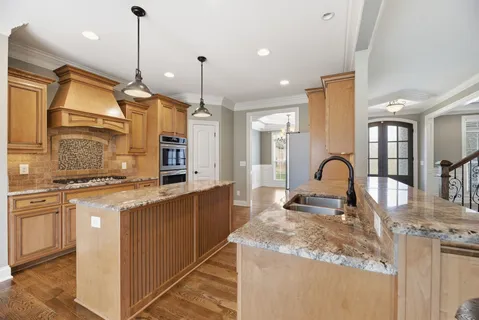 a open kitchen with a stove a sink dishwasher a kitchen island with wooden floor and cabinets