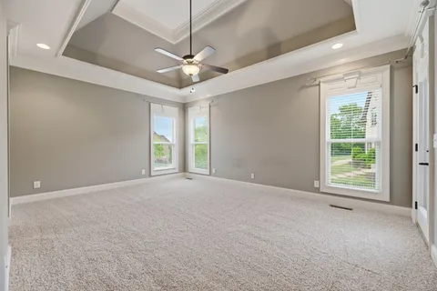 an empty room with windows and ceiling fan