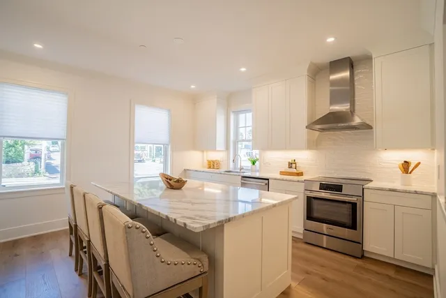 a kitchen with stainless steel appliances granite countertop a sink a stove and a wooden floors