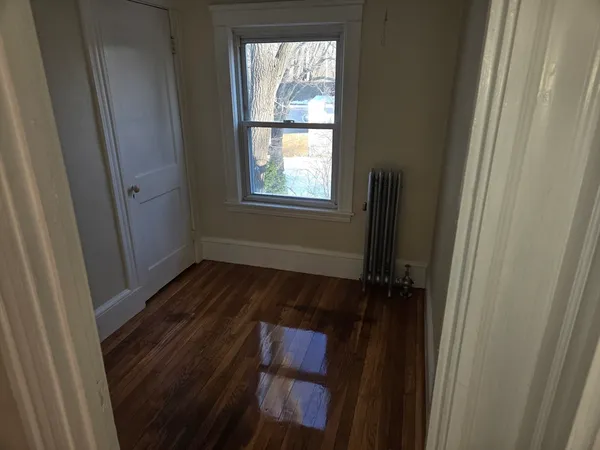 a view of hallway with window and wooden floor