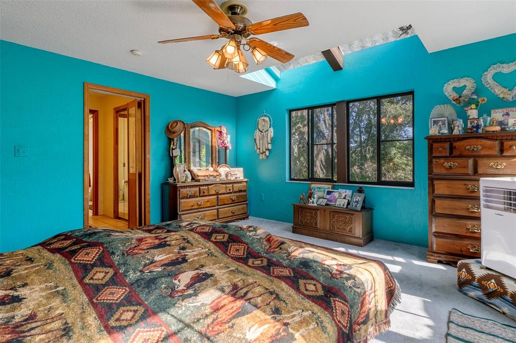 27910 Debbie Road Leesburg, FL 34748 - Photo 38 of 99 a bedroom with a bed and a chandelier